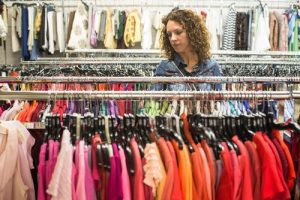 A woman browsing a thrift store to buy clothing