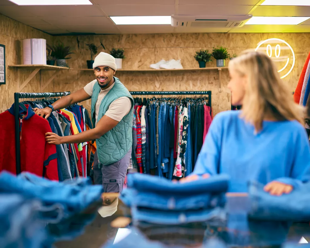 Couple Or Sales Assistants Working Or Looking At Clothes In Pop Up Fashion Store