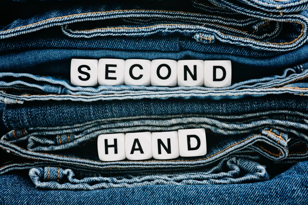 Second hand, Vintage Shopping, slow fashion, Sustainable fashion concept. Stack of blue old denim jeans with the words second hand.